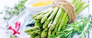 A close up of asparagus with some sauce in the background