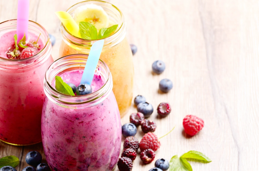 Two jars of fruit smoothie with a straw.