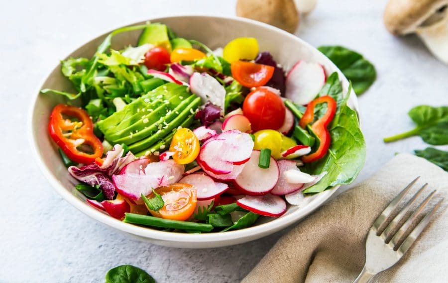 A bowl of salad with lettuce, tomatoes and radishes.