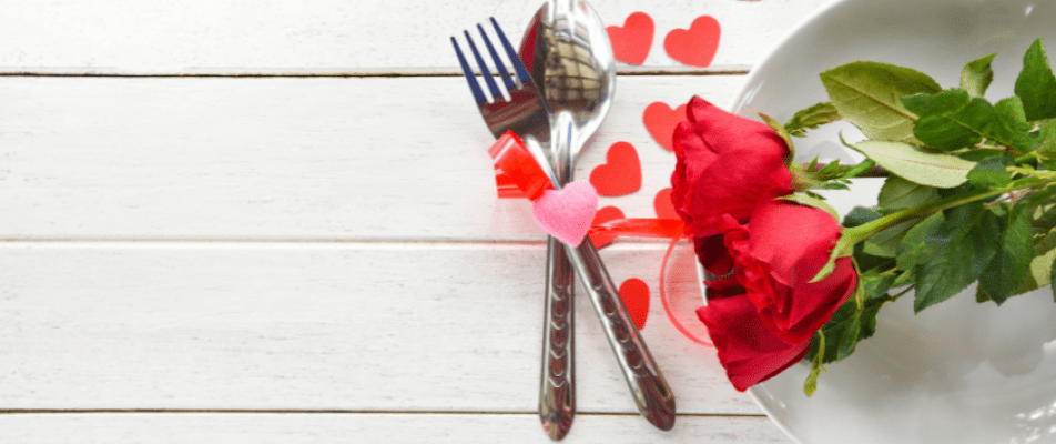 A spoon and fork with hearts on the table.