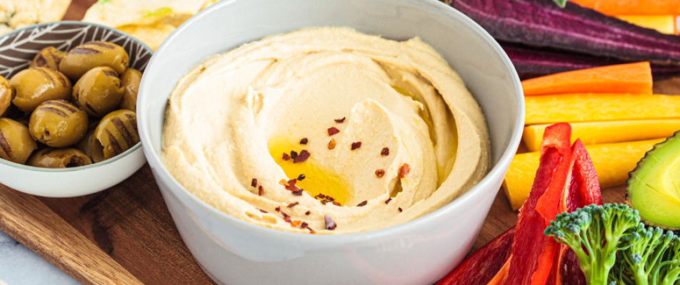 A bowl of hummus with red pepper on top.