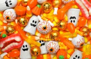 A pile of candy with halloween decorations on top.