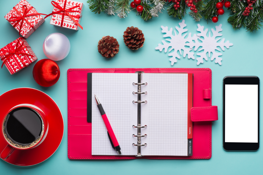 A red notebook and pen on top of a table.