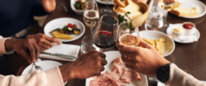 A group of people holding wine glasses at a table.