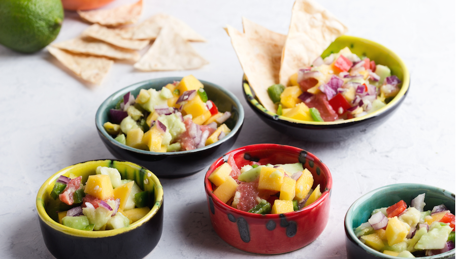 A table topped with bowls of food and tortilla chips.