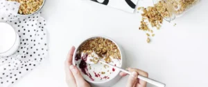 A person is eating cereal with yogurt and fruit.