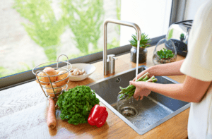 A person is washing vegetables in the sink.