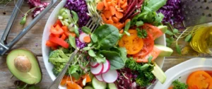 A plate of salad with carrots, radishes and lettuce.