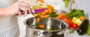 A person is cutting carrots into some food