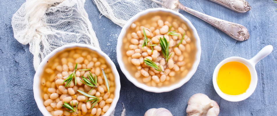 Two bowls of beans with herbs on a table.