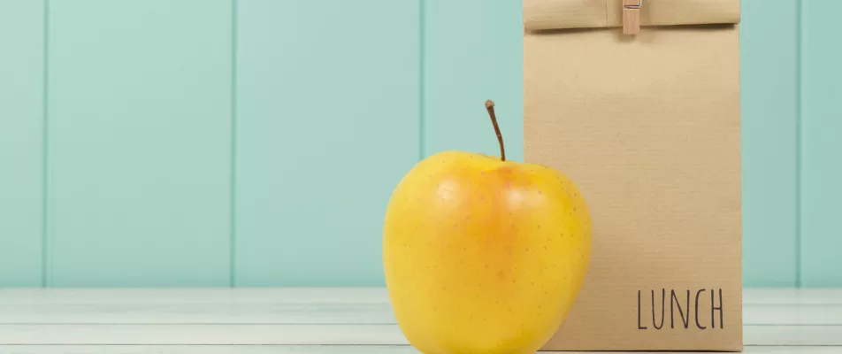 A yellow apple sitting on top of a table.