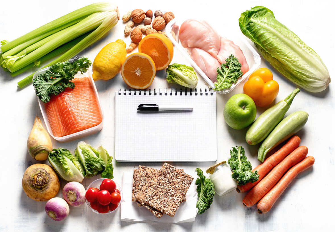 A notebook surrounded by fruits and vegetables