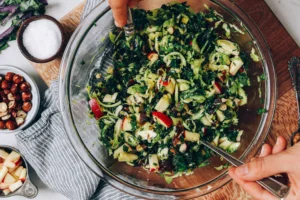 A person is holding a fork and salad in a bowl.