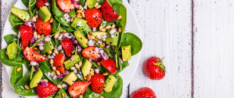 A white plate topped with salad covered in strawberries.