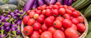 A pile of tomatoes and purple potatoes in the background.