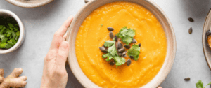 A person holding their hand over a bowl of soup.