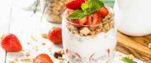 A close up of a glass with yogurt and strawberries