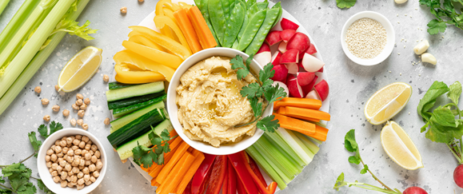 A plate of food with various vegetables and hummus.