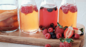 A wooden board with three jars of fruit juice.