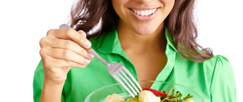 A woman holding a fork and eating food.