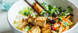 A salad with tofu and sesame seeds on top.