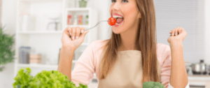 A woman holding a spoon with tomatoes on it.