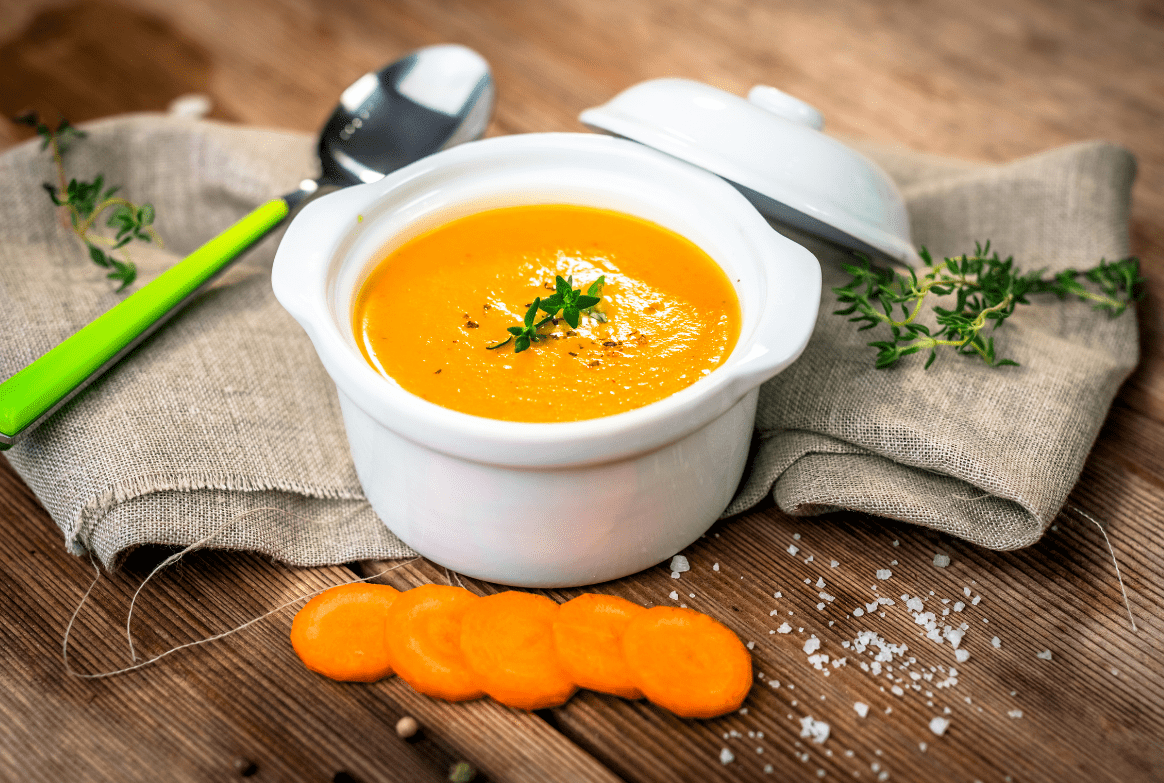 A bowl of soup with carrots on the side.