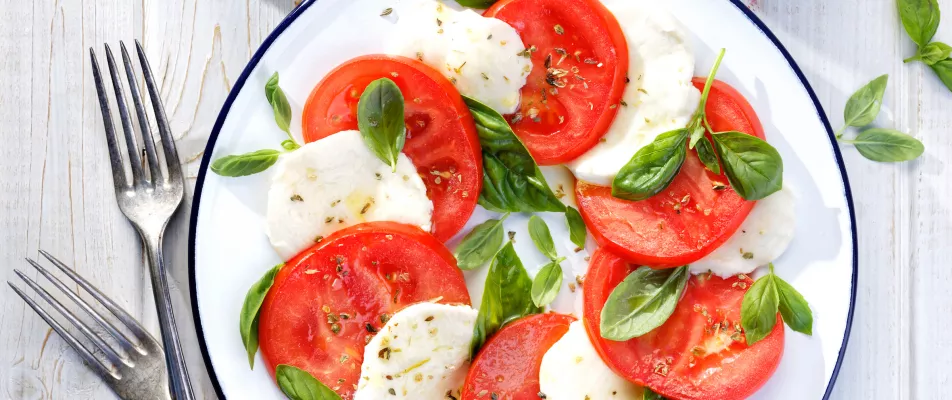 A plate of tomatoes and mozzarella with basil.