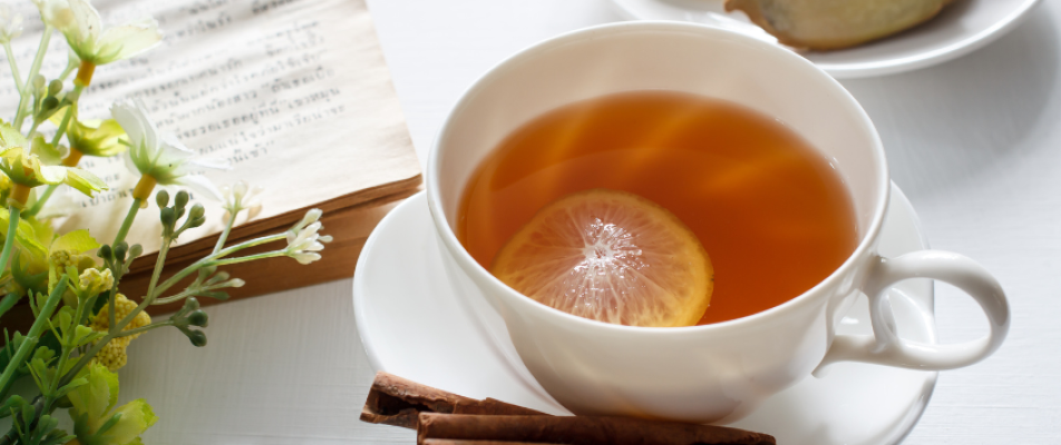 A cup of tea with an orange slice in it.