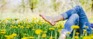 A person 's feet in the grass with yellow flowers.