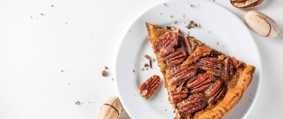 A piece of pecan pie sitting on top of a white plate.