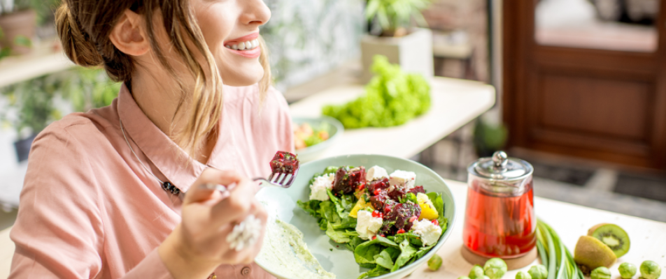 A woman holding a fork and eating salad.