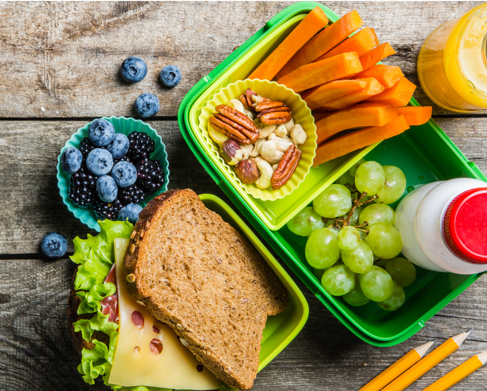 A wooden table topped with green containers filled with food.