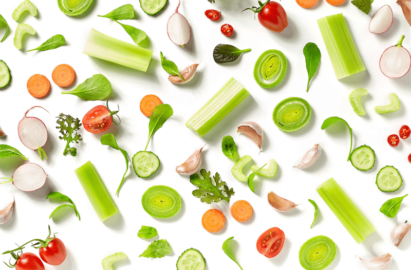 A white table topped with lots of different vegetables.