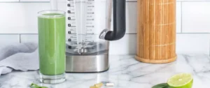 A blender with a green smoothie next to it.