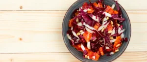 A bowl of salad with dressing on top.