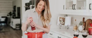 A woman is cooking in the kitchen with red pots.