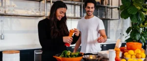 A man and woman in the kitchen preparing food.