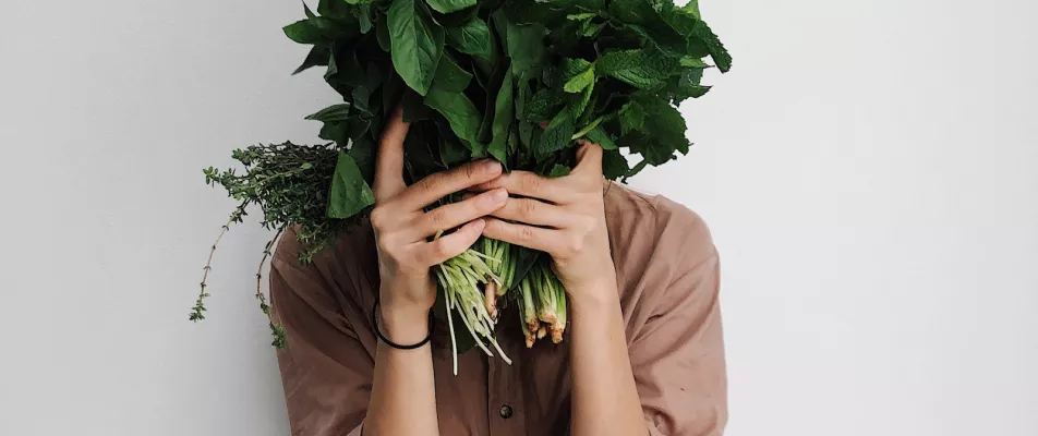 A person holding some vegetables in front of their face