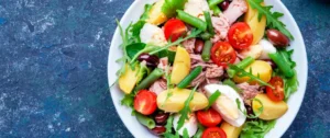 A bowl of salad with tomatoes, pineapple and greens.