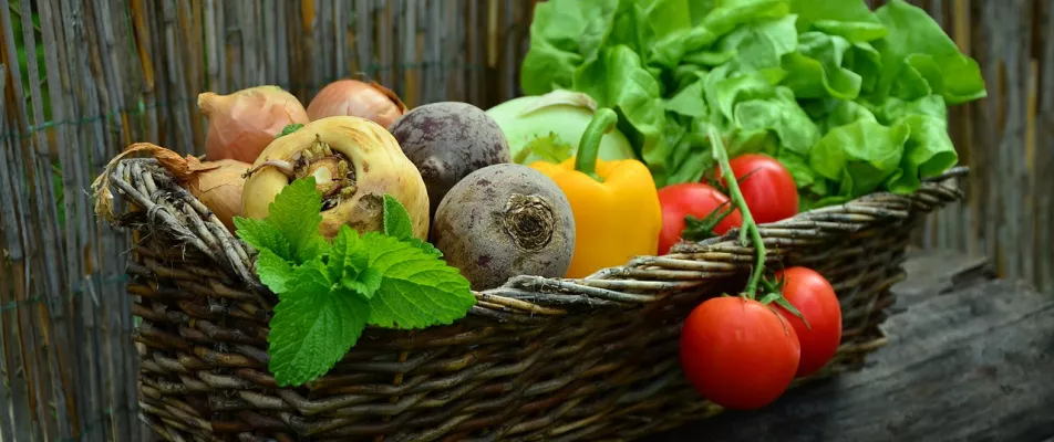 A basket of vegetables is sitting on the table.